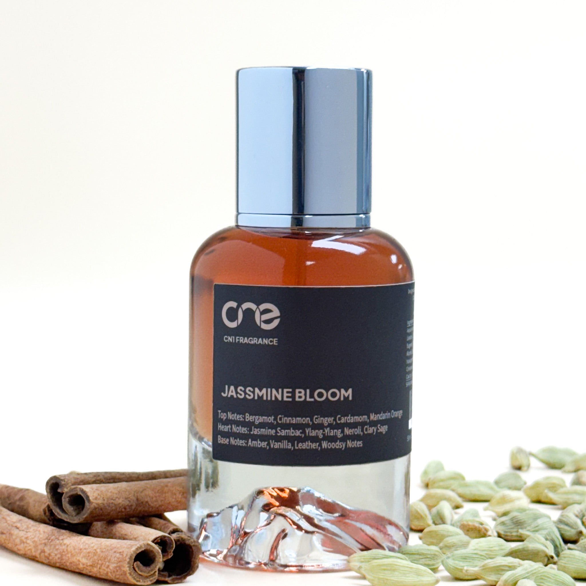 Bottle of Cre Fragrance Jasmine Bloom with cinnamon sticks and green beans on a white background