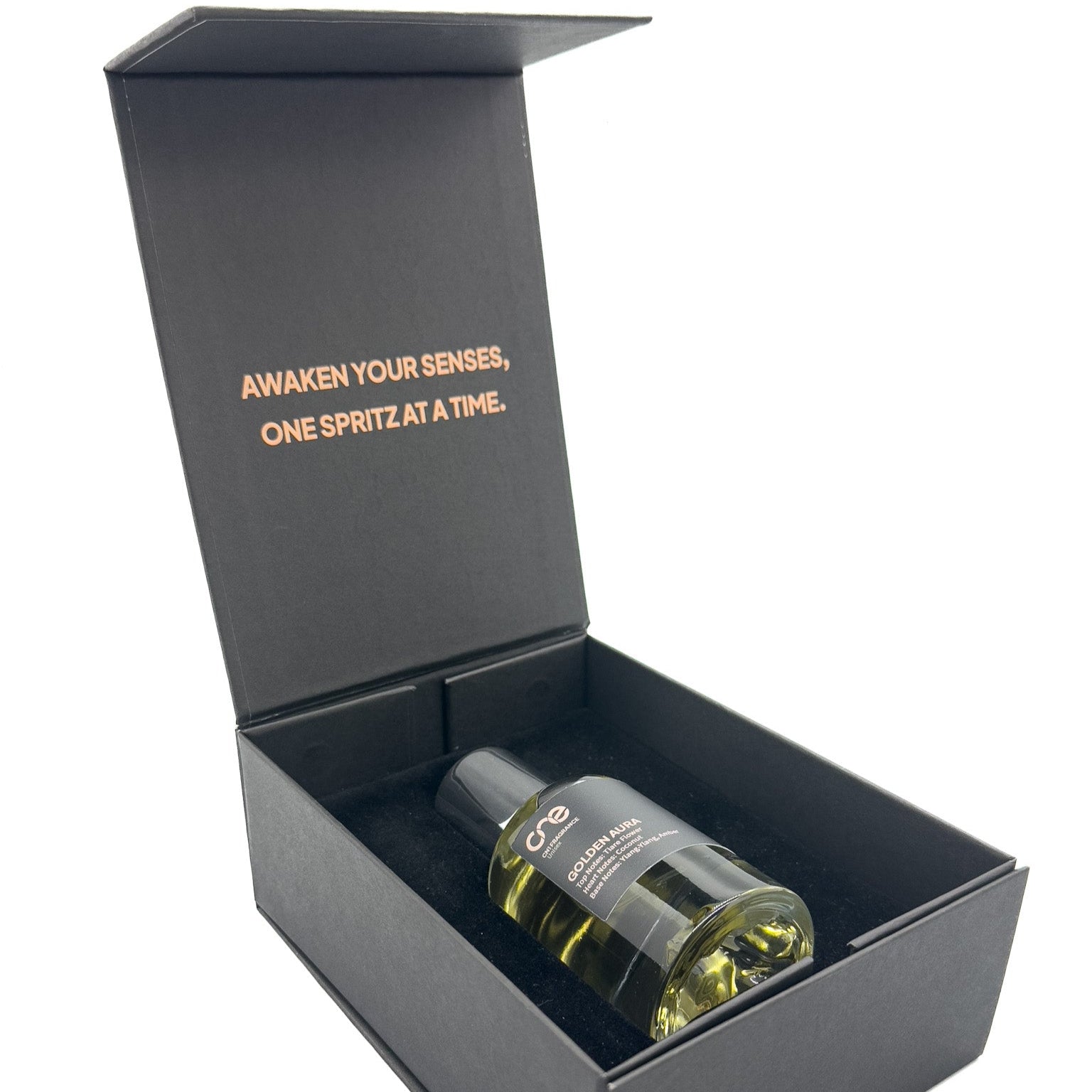 Close-up of Golden Aura by CN1 Fragrance bottle nestled among ylang-ylang blossoms, amber resin chunks and vanilla beans on a wooden table