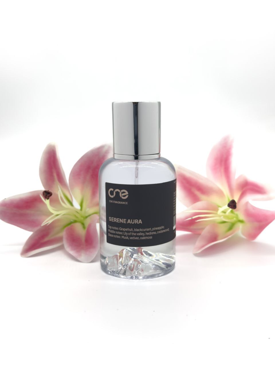 Serene Aura by CN1 Fragrance 50 ml clear glass bottle with golden liquid, styled with grapefruit slices, blackcurrants, and lily of the valley on a marble surface.